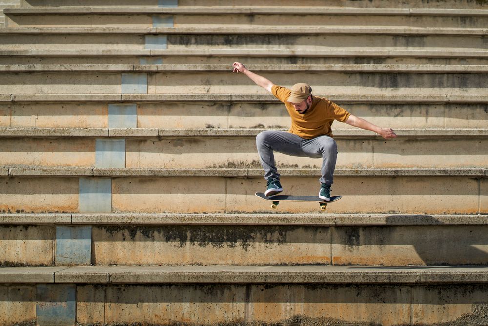 A young man jumping with his skateboard on the bleachers