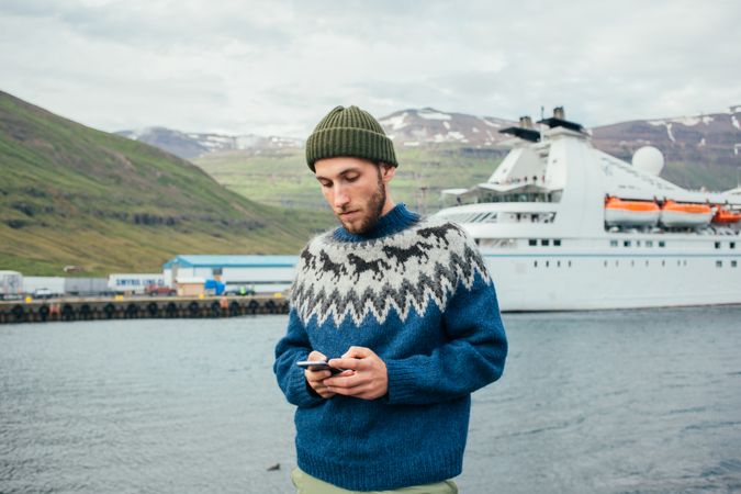 Scandinavian man texting with a cruise ship in the background