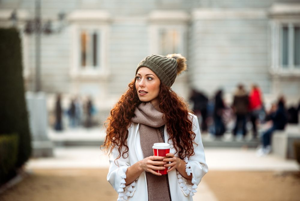 Woman drinking coffee wandering in the streets of Madrid on winter