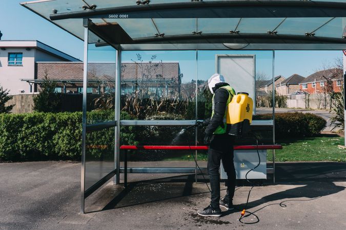 Man sanitizing bus station bench