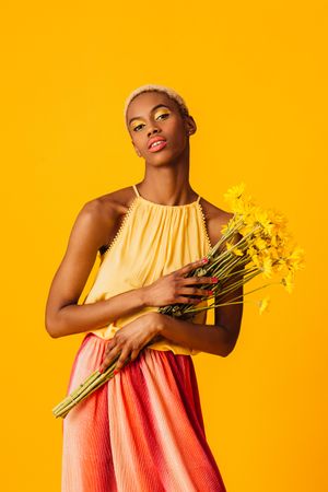 Black woman with short blonde hair holding yellow flowers