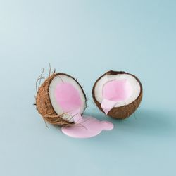 Coconut cracked in half with pink milk pouring out