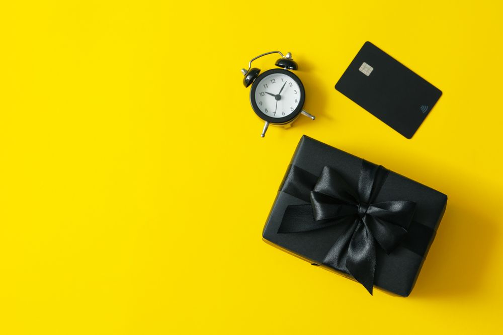 Gift box, alarm clock and card on yellow background