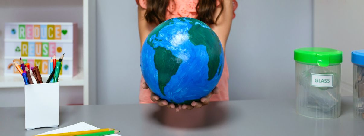 Female student holding a handmade globe world at ecology classroom