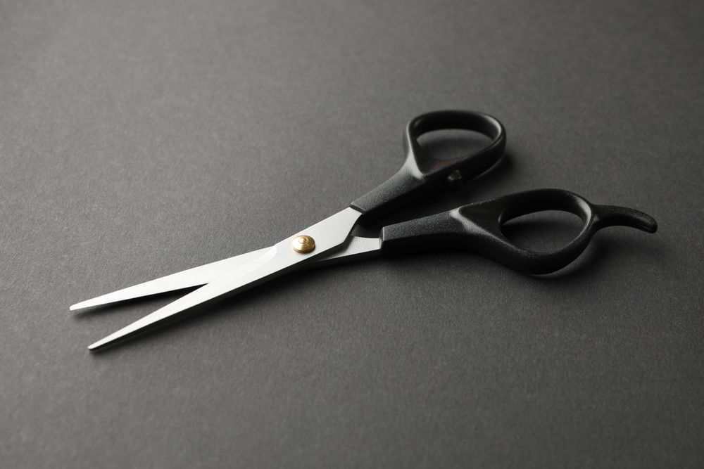 hairdresser scissors on dark background, space for text