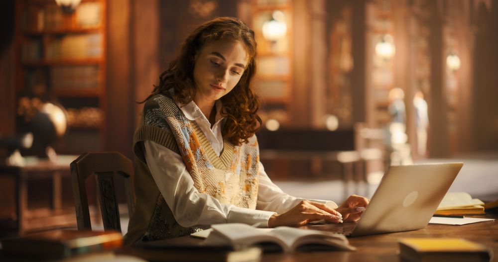 Serene Young Woman Engaged in Studying With Laptop and Books in a Classical Library Setting