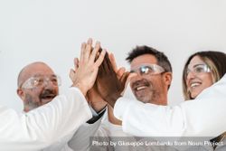 Group of joyful scientists high-fiving in a lab, showcasing teamwork and diversity in research 0WOPRW