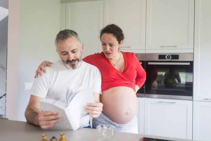 Pregnant woman and male partner going through recipe book together