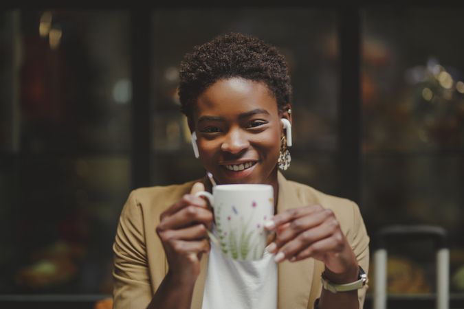 Black woman with cup of drink sitting at table in cafe