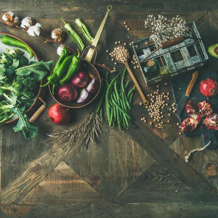 Assortment of seasonal winter vegetables, pomegranates, peppers, broccoli on wooden table