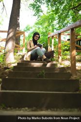 Woman sitting at the top of forest stairs with a book 5RkzN4
