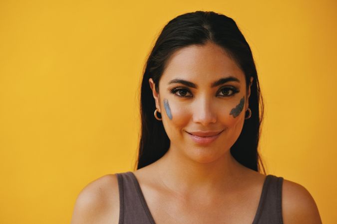 Smiling Latina woman standing with mud mask on face, copy space