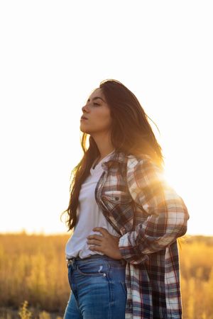 Young woman dressed in vintage clothing watching the sunset in the field