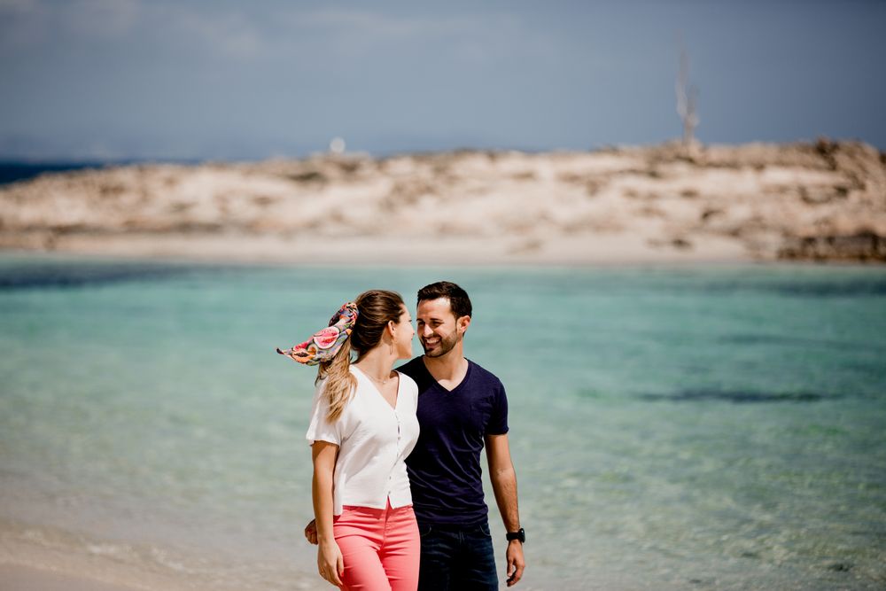 Happy couple walking on turquoise seashore in summer light