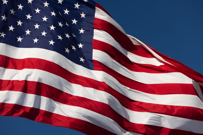 American Flag Waving In Wind Against a Deep Blue Sky.