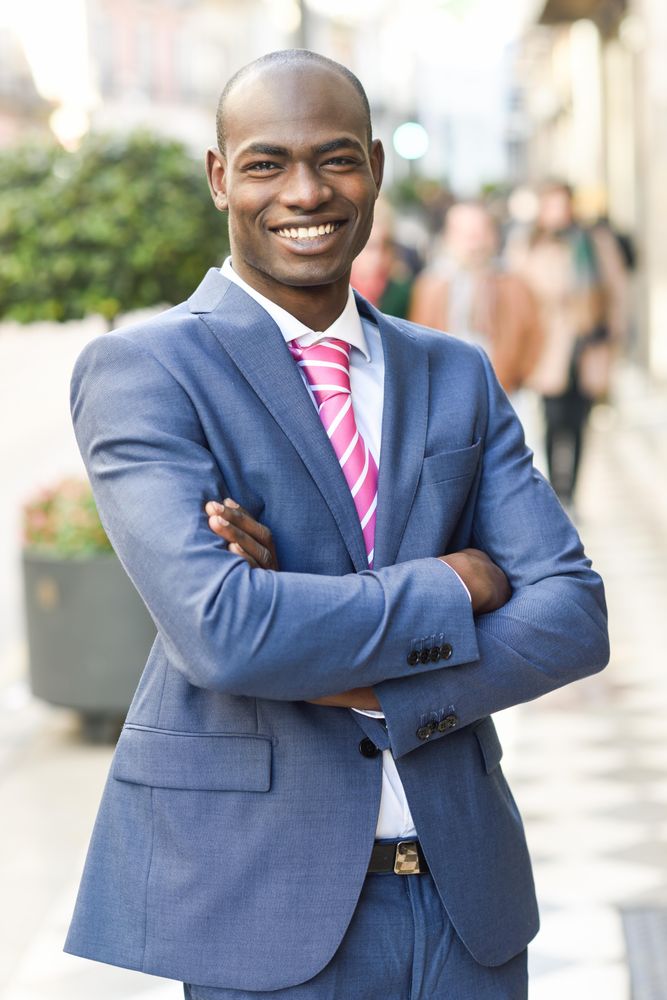 Happy male in business attire standing with arms crossed European street