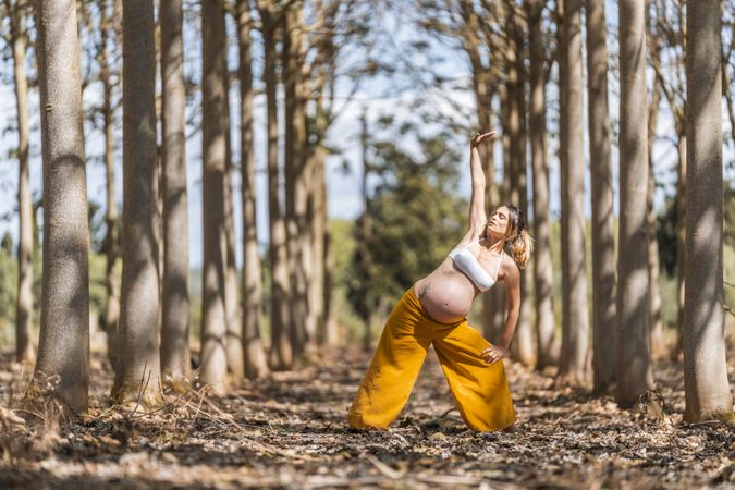 Concentrated adult expectant mother practicing yoga in park