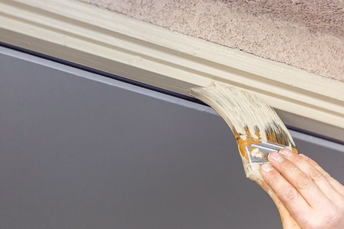 Professional Painter Cutting In With Brush to Paint House Door Frame.
