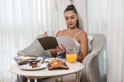 Woman reading magazine during breakfast