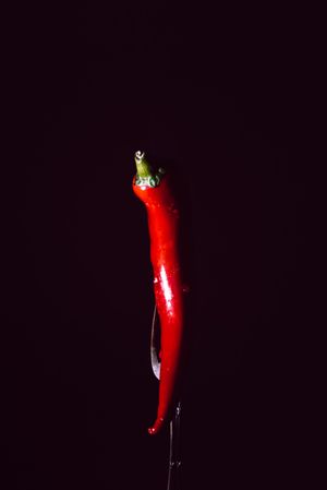 red chili pepper in fork on a dark background with smoke
