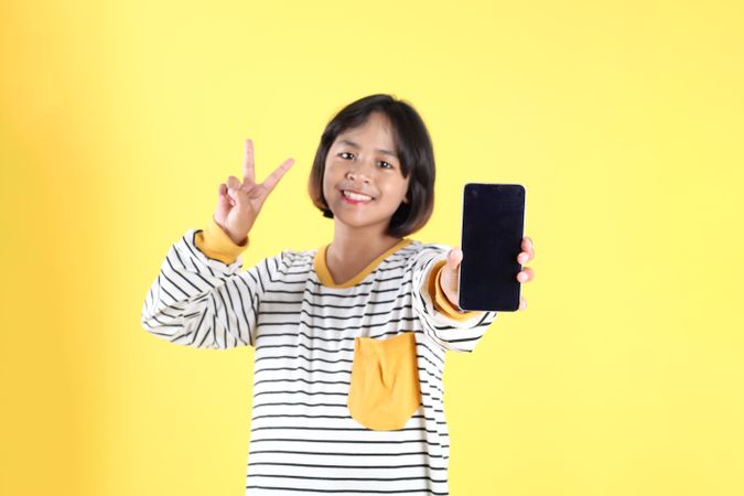Indonesian Girl Kids Making Peace Sign Holding Mobile Phone