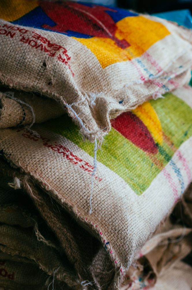 Close up of three colorful burlap bags holding raw coffee beans