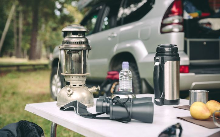 Oil lamp, thermos and binoculars over camping table