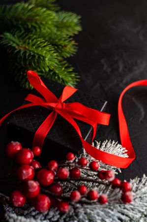 Christmas concept of gift box with holly and branches on concrete background