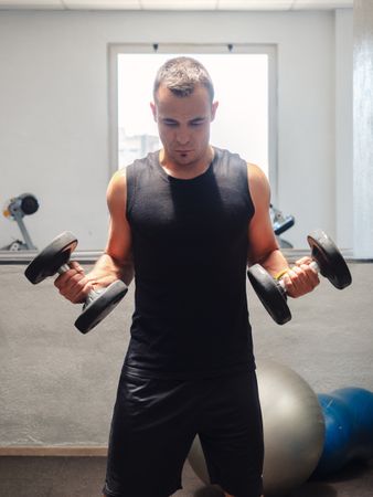 Strong man exercising with dumbbells on bench