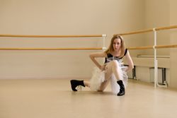 Ballerina in shoes and tutu, kneeling in modern dance pose
