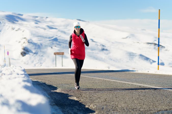 Young woman enjoying running on road in winter clothes