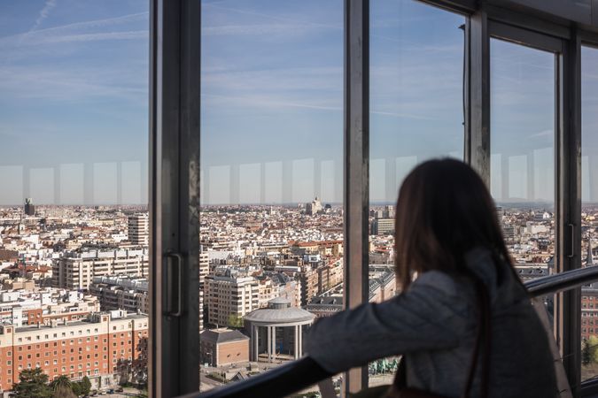 Anonymous woman looking out balcony window