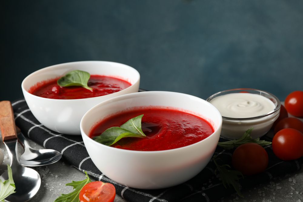 Tomato soup bowls surrounded by ingredients on grey kitchen counter