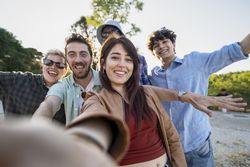 Happy diverse friends taking outdoor group selfie during summer day trip