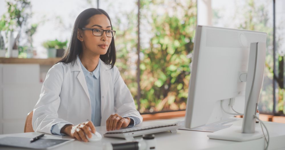 Portrait of an Asian Medical Health Care Professional Working on Desktop Computer in Hospital Office.