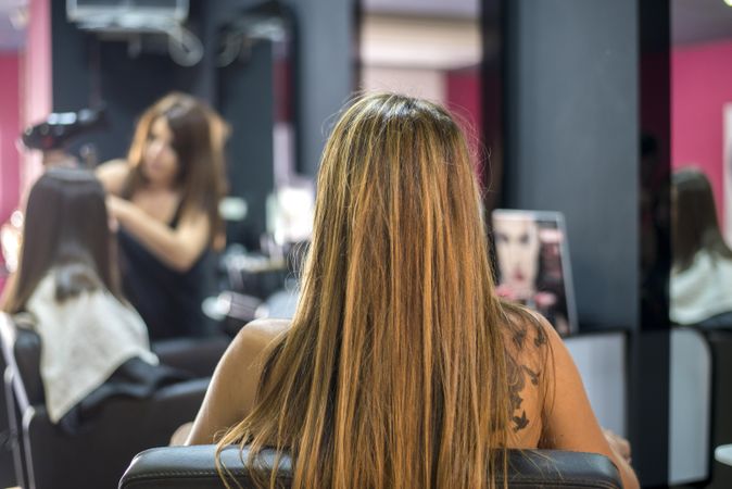Rear shot of woman with long hair sitting in salon chair