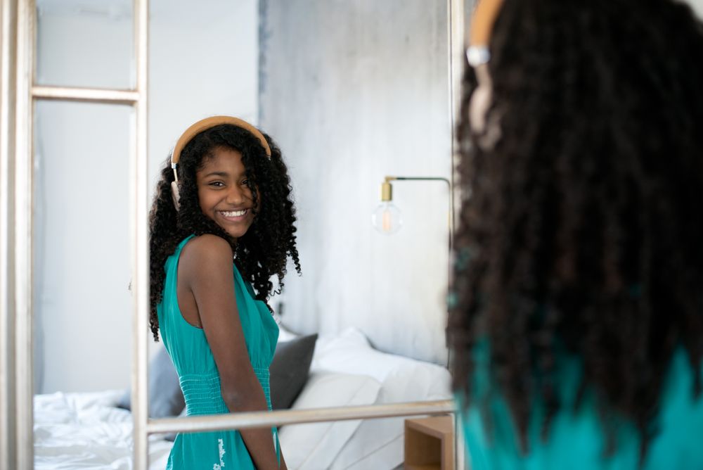 Black girl with headphones dancing in mirror