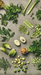 Arrangement of fresh green sliced garden vegetables on concrete surface