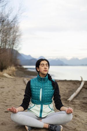Young woman meditating on the lake shore