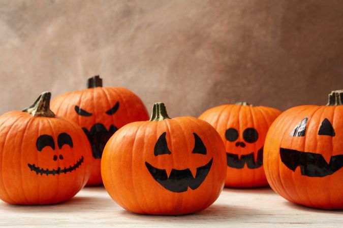 Funny halloween pumpkins against brown background, space for text