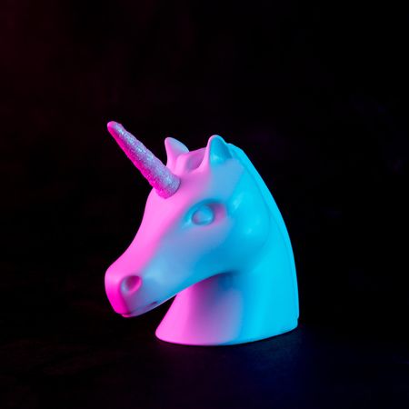 Painted unicorn head in bold pink and blue neon colors on dark background