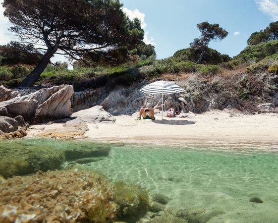 Man resting under umbrella on sandy shore