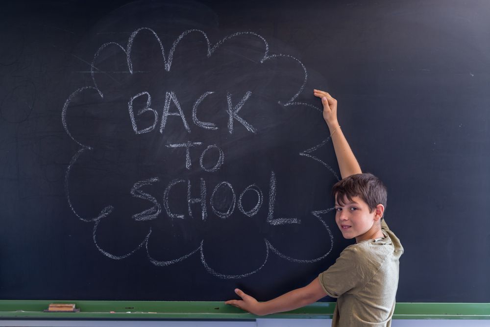 Boy standing at chalkboard with "back to school"