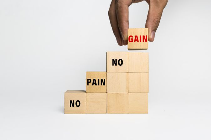 male hand put a wooden blocks with no pain no gain words isolated on plain background