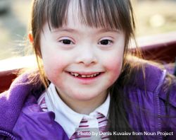 Smiling young girl with Down syndrome dressed in a purple coat 5kQAGb