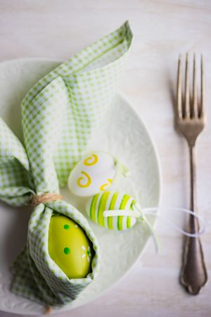 Easter holiday concept of green Easter egg wrapped like rabbit with napkin