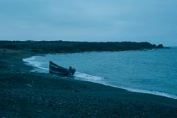 Small motor boat moored on dark Lanzarote beach