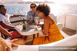 Cheerful women drinking wine and enjoying the open water with male friends 5Q1PV5