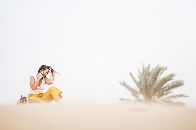 Happy woman using smartphone in desert