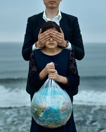 Father closing daughter's eyes who is holding the globe